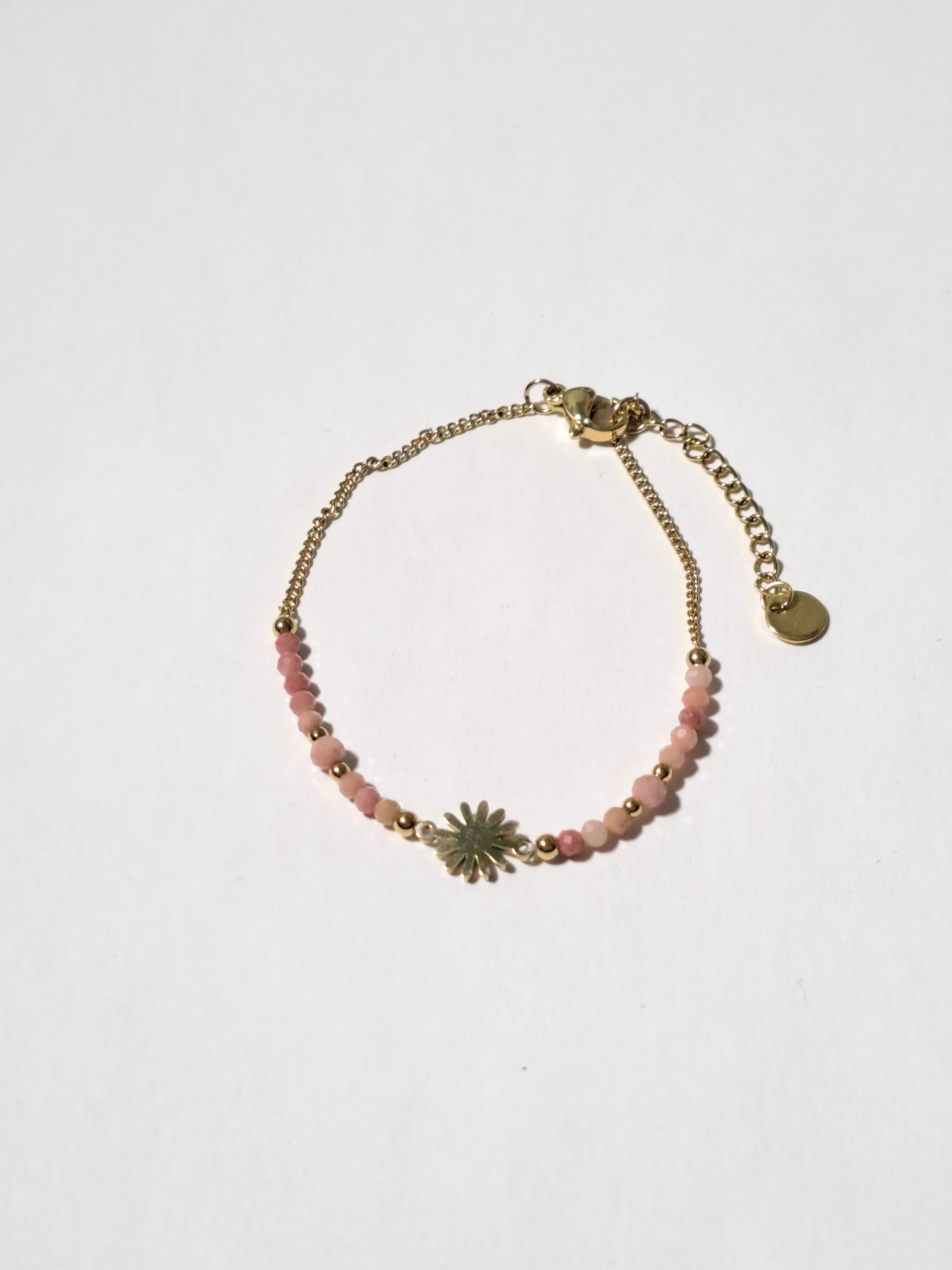 Bracelet délicat orné d’un charm soleil doré & de perles roses.