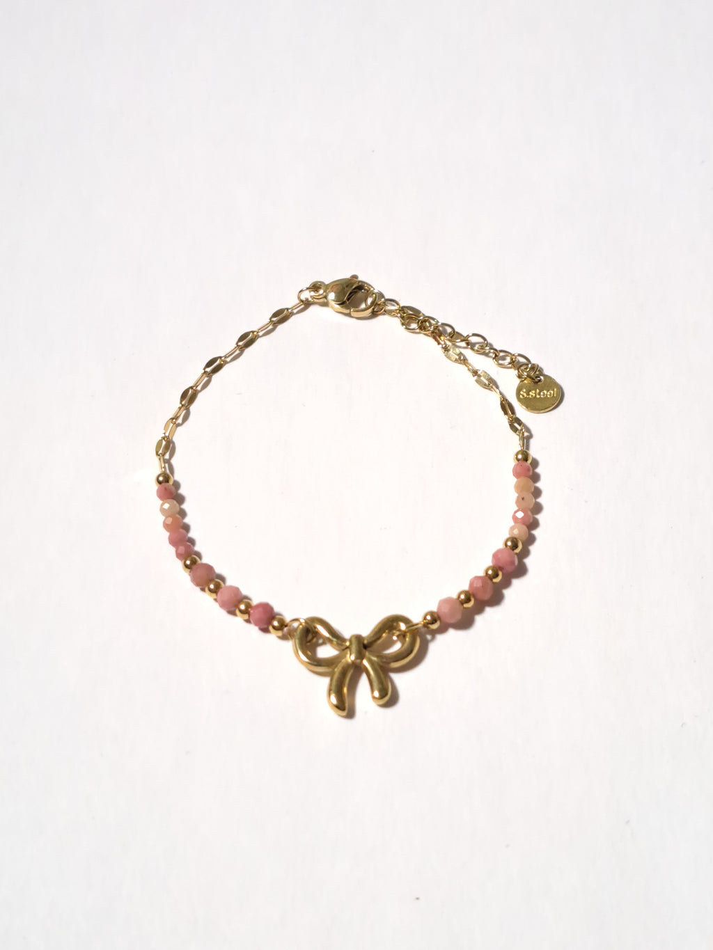 Bracelet doré orné d’un charm nœud et perles roses