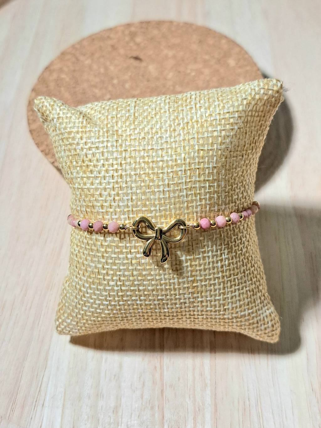 Bracelet doré orné d’un charm nœud et perles roses