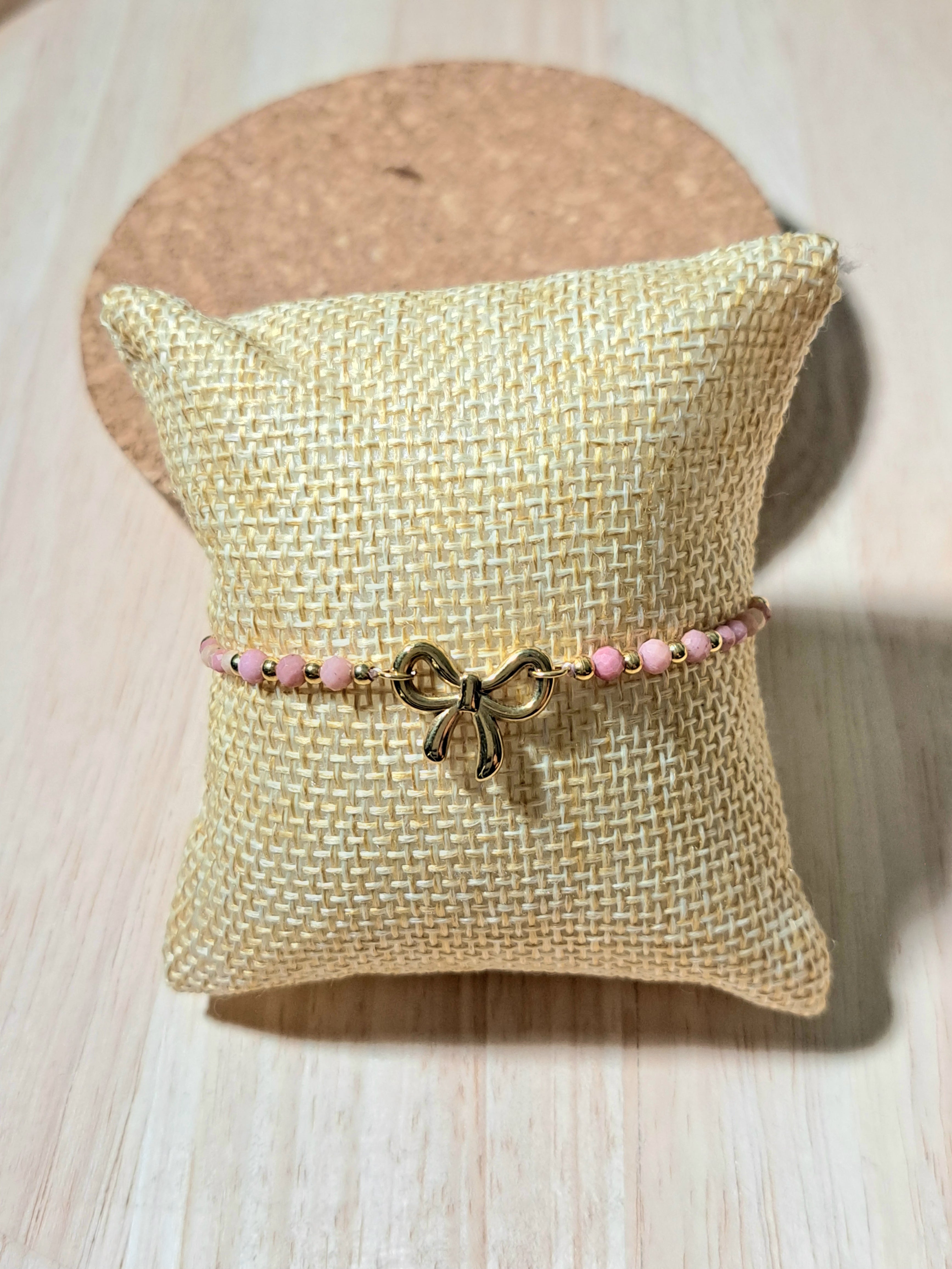 Bracelet doré orné d’un charm nœud et perles roses